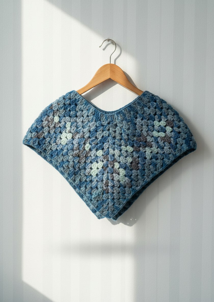 The Shoulder Wrap in blue on a hanger — handmade crochet wrap